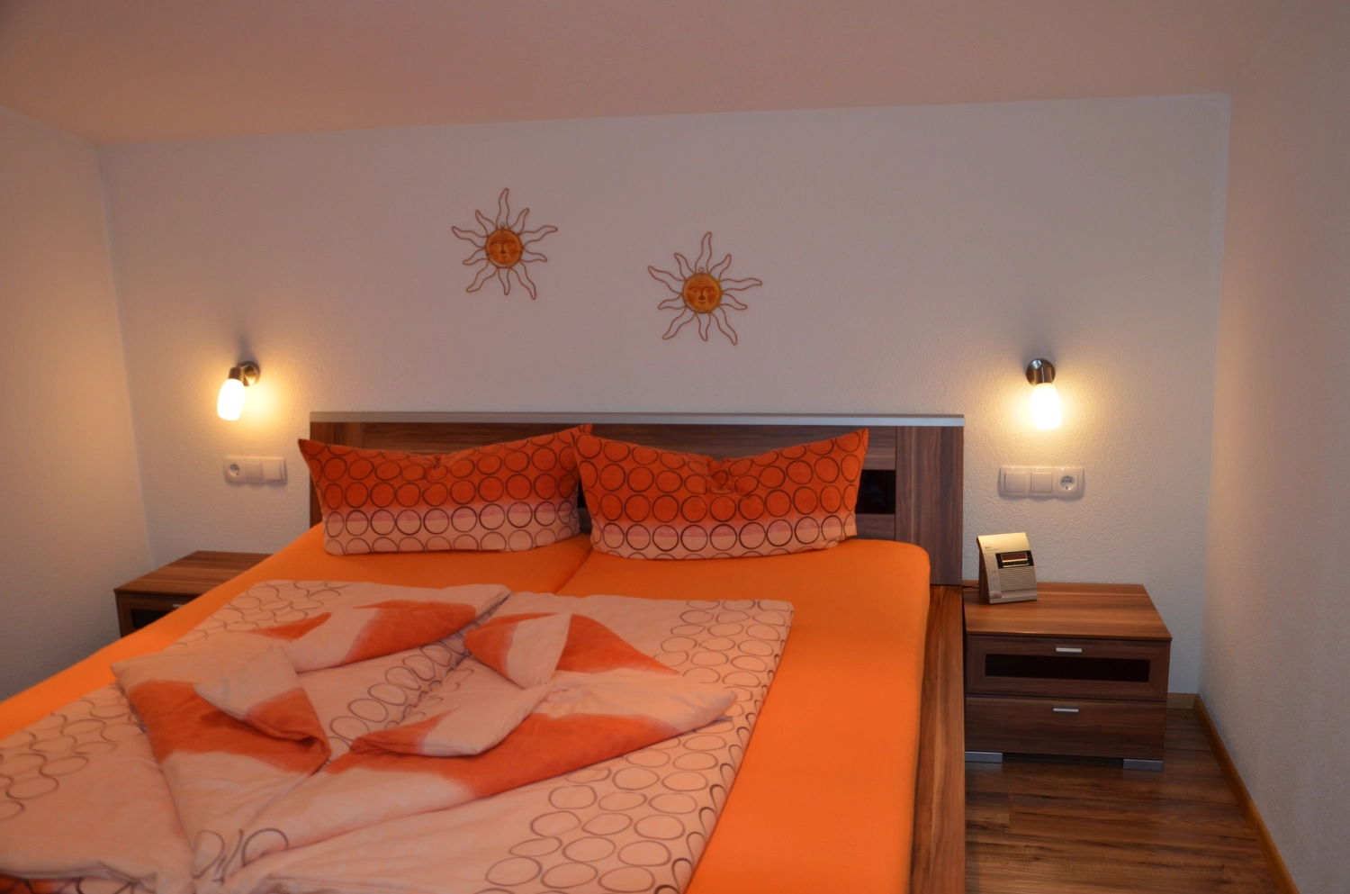Doppelbett mit oranger Bettwäsche im Appartement Moritz